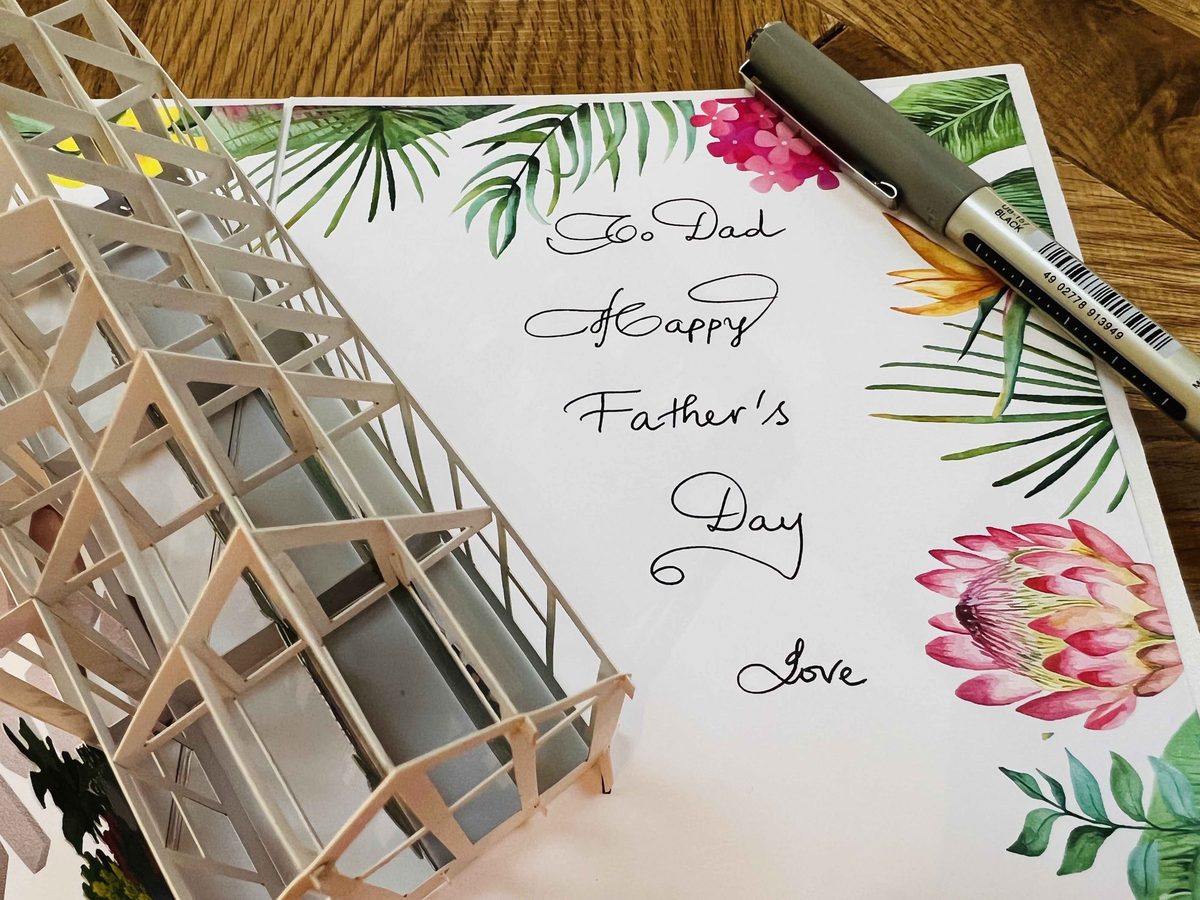 A pop-up card with 'To Dad, Happy Father's Day, Love' written inside by hand in elegant cursive